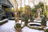 Jardin à la française avec maison d'été, étang circulaire et conifères dans des pots en terre cuite - The Old School House, Great Bentley, Essex en janvier