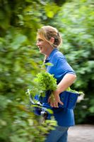 Jardinier transportant un panier d'herbes à travers le jardin à l'école de cuisine Ballymaloe