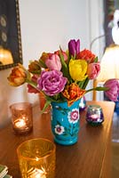 Tulipes dans un vase sur une commode avec des bougies dans des porte-verres