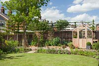 Étape par étape - Vue d'ensemble du jardin avec serre, bordure végétale surélevée et charmes blanchis