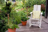 Terrasse en bois surélevé avec chaise adirondack, pots et bougies - Brook Hall Cottages, Essex NGS