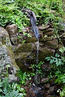 Caractéristique de l'eau naturaliste à l'aide de rondins pourris sur un mur de pierre sèche moussue