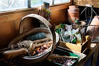 Banc de remise en pot au printemps avec des paquets de graines, des pots de fleurs en terre cuite, des ensembles d'oignons et des graines de haricot, UK, avril