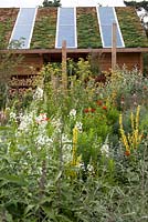 Pavillon de jardin avec panneaux solaires et plantes sur le toit.