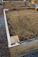 Boîte en chêne remplie d'un mélange de terre, de sable tranchant et de grains fins à utiliser comme bordure végétale surélevée