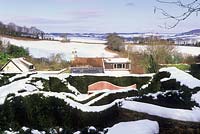 Vue sur les jardins de haies de la maison. Haies d'ifs surmontées de neige - Veddw House Garden, Devauden, Monmouthshire, Wales. Royaume-Uni