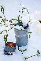 Brins de gui neigeux en pot d'argent avec bougie chauffe-plat