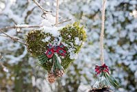 Coeur de mousse neigeuse avec ruban affiché suspendu à une branche
