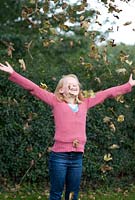 Jeune fille jetant et s'amusant avec les feuilles d'automne, octobre