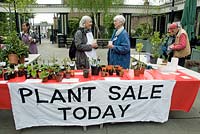 Bannière disant vente de plantes aujourd'hui avec deux femmes parlant derrière l'étal, Highbury Barn, London Borough of Islington, Royaume-Uni
