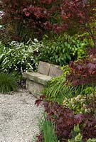 Siège en pierre à côté d'un chemin de gravier avec des plantations d'influence japonaise pour offrir un lieu de méditation calme - 'Il y a un endroit dans les bois où l'Est rencontre l'Ouest' Show Garden, Gold Award, Malvern Spring Show 2013
