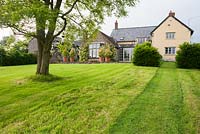 La maison est située sur un site plat au sommet d'une longue pelouse en pente, offrant une vue sur la campagne environnante. Ashley Farm, Stansbatch, Herefordshire, Royaume-Uni
