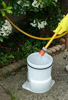 Ajouter de l'eau au désherbant dans un pulvérisateur de jardin, avec des gants de protection en caoutchouc pour la sécurité