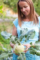 Femme tenant le chou-rave cultivé à la maison - Brassica oleracea var. gongylodes 'Wiener '.
