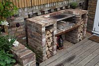 Barbecue avec bûches coupées sur un patio en bois