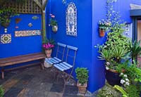 Petit jardin de ville - Cour avec murs bleu cobalt, chaises de café bleues et sol en ardoise.