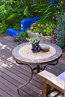 Terrasse en bois avec table en mosaïque et mur de soutènement en rendu bleu. Jardin de petite ville, Brighton, UK