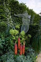 Parterre de fleurs colorées avec sculpture de fil et plantes, y compris Echium pinnata et lupins