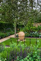 Jardin avec potager intégré, pelouse avec sculpture et allées entre parterres et parterres mixtes