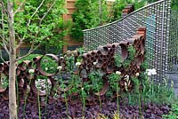 Le jardin SeeAbility, la structure des tubes métalliques rouillés et le rideau sphère en acier le long des parterres de fleurs.
