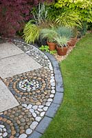 Effet de mosaïque en pierre sur le patio et feuillage coloré mélangé d'Acer et d'herbes en pots