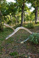 Sculpture en bois parmi les arbres par Marc Nucera. Provence, France, Domaine de la Verriere