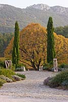Sculptures en bois de Marc Nucera de chaque côté d'un tilleul de couleur automne. Provence, France, Domaine de la Verriere