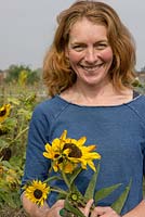 Dame coupant des tournesols pour la décoration florale, souriant à la caméra