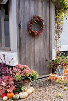Décoration rustique d'automne à l'extérieur de la porte du chalet avec couronne, hortensias, courges, pommes