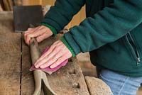 Poncer les parties en bois de la bêche pour éliminer les éclats et se préparer à l'huilage