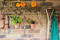 Porte-outils rustique avec des plantes en pots en terre cuite et des outils rénovés.