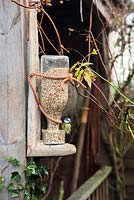 Mangeoire à oiseaux rustique fait maison avec mésange bleue - Cyanistes caeruleus, Parus caeruleus perché sur le bord de la mangeoire
