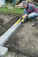 Construction de serres - blocs de béton annuels entre les coins pour préparer la base en aluminium et vérifier le niveau