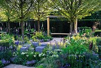 L'espoir à l'horizon. Banc incurvé sous pergola et blocs de granit placés dans des parterres de fleurs