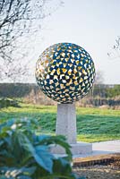 Le manteau - une sphère en bronze verigris composée de dizaines de pétales de bronze individuels soudés ensemble