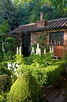 Le jardin Topiarist à West Green House - Chemin de pierre menant au jardinier en brique. Boîte topiaire. Lupins blancs et campanules.