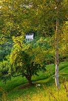 L'exèdre vu à travers les arbres. Jardin Rococo de Painswick, Gloucestershire