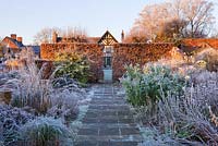 Wollerton Old Hall, Shropshire - Jardin d'hiver dans le gel - chemin de la maison à l'aube avec haie de hêtres coupée et parterres de fleurs givrées