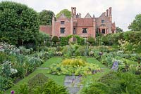 Jardin submergé formel en été avec Alchemilla mollis, Geranium, Rosa, Papaver, Feverfew avec Manor House derrière. Chenies Manor, Buckinghamshire