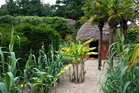 Jardin modèle représentant l'Afrique avec une hutte de boue, des bananes, des palmiers et des herbes ornementales. Seend, Wiltshire