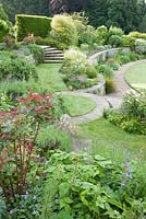 Des terrasses sinueuses incurvées relient le niveau de la maison à la pelouse en contrebas, avec des allées herbeuses et des parterres de roses, de lavande et de romarin. Forest Lodge, Pen Selwood, Somerset, Royaume-Uni