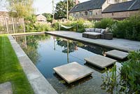 Jardin de la piscine avec étang de baignade, terrasse en bois, hamacs et sièges entourés de plantations naturalistes. Ancien presbytère, Batcombe, Somerset, UK