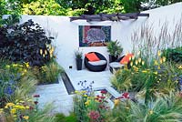 Hedgehog Street. Jardin de la cour, chaises contemporaines avec coussins. Kniphofia, stipa, calamagrostis, achillea