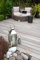 Coin salon de terrasse en bois dur Ipe avec des meubles en rotin et des lanternes avec des bougies