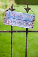 Panneau en bois sur portail en fer forgé, lisant 'I ' m dans le jardin '.