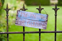 Panneau en bois sur portail en fer forgé, lisant 'I ' m dans le jardin '.