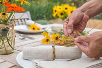 Femme créant des décorations de table à l'aide de rudbeckia, tithonia et stipa gigantea grass