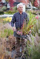 Homme portant une caisse de plantes vivaces et d'herbes sélectionnées à la pépinière.