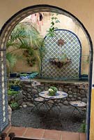 Vue à travers l'arche vers le coin salon avec une pièce d'eau et diverses plantes succulentes en pot. Jardin de Jim Bishop, San Diego, CA