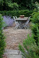Haie Taxus baccata - If, patio en pierre de chiffon avec table et chaises à lattes en ardoise antique, et parterre de Nepeta 'Géant des Six Collines' - Catmint